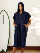 Modelo usando o Poncho Adulto Canguru Azul Marinho da Greenish, com capuz e bolsos, ideal para a praia.
