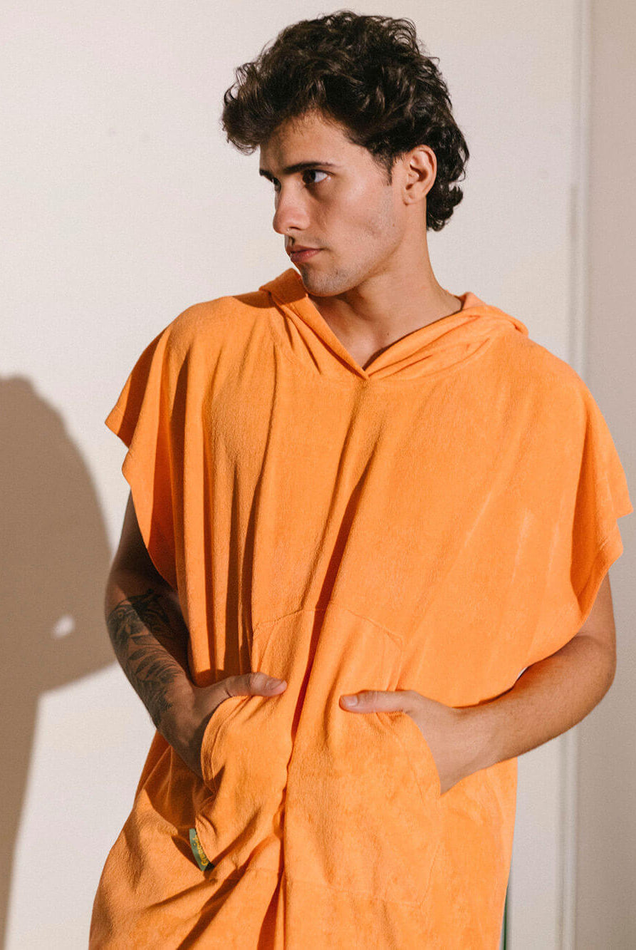 Homem usando poncho adulto cor laranja da Greenish, com bolsos canguru e tecido atoalhado.