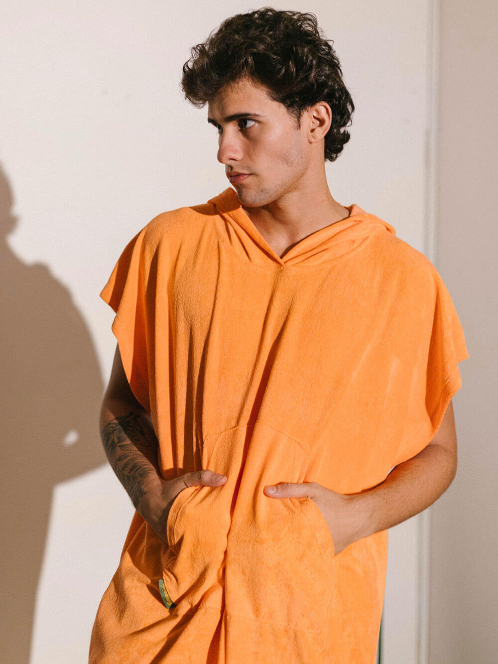 Homem usando poncho adulto cor laranja da Greenish, com bolsos canguru e tecido atoalhado.