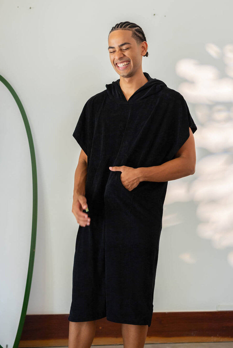 Homem sorrindo usando poncho adulto Black da Greenish, ideal para praia e esportes aquáticos.