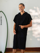 Homem sorrindo usando poncho adulto Black da Greenish, ideal para praia e esportes aquáticos.