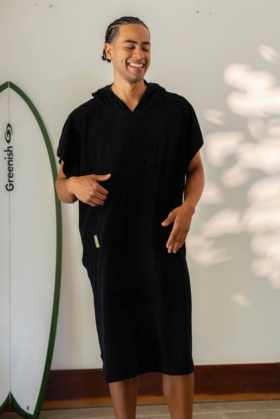 Homem sorridente usando poncho adulto Black da Greenish, ideal para praia e esportes aquáticos.