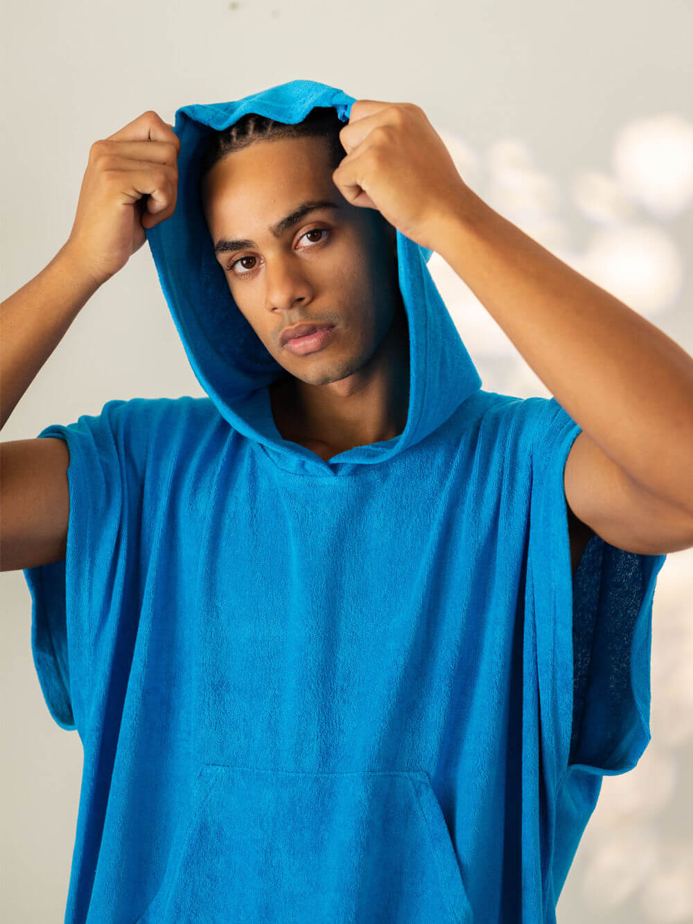 Jovem usando poncho adulto canguru turquesa da marca Greenish, perfeito para a praia e secagem rápida.