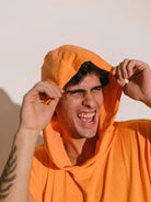 Homem sorrindo vestindo poncho adulto Greenish cor coral com capuz, destacando seu conforto e estilo.