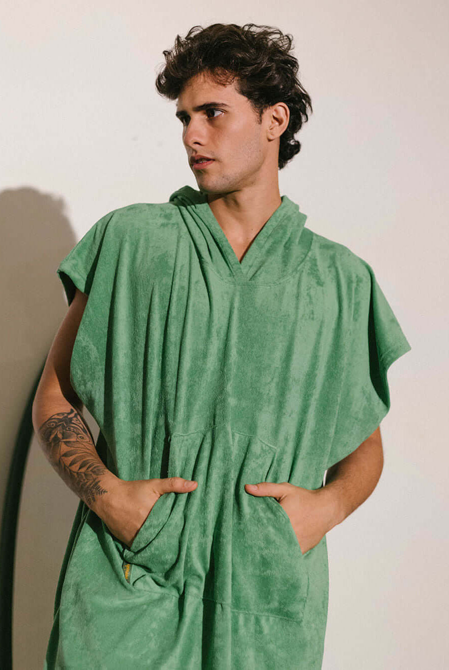 Homem usando poncho verde adulto da Greenish, tecido atoalhado com bolsos, ideal para praia e esportes aquáticos.