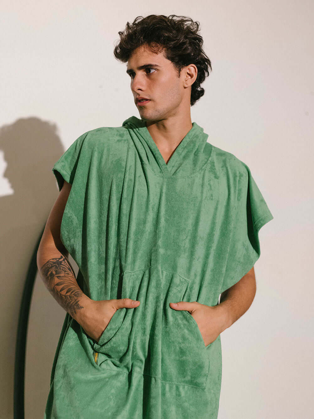 Homem usando poncho verde adulto da Greenish, tecido atoalhado com bolsos, ideal para praia e esportes aquáticos.