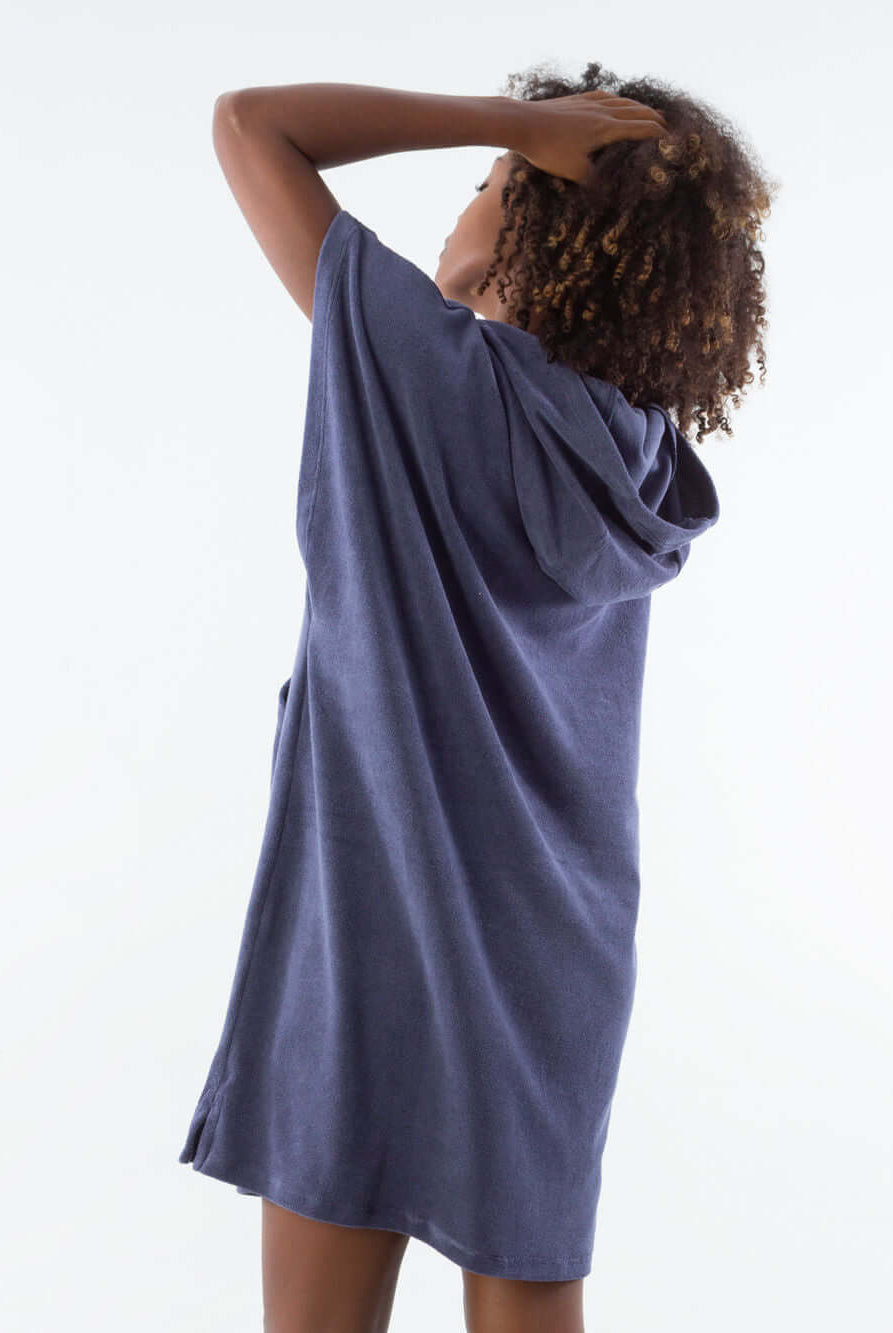 Model wearing a navy blue short towel poncho with hood, showcasing the back view.