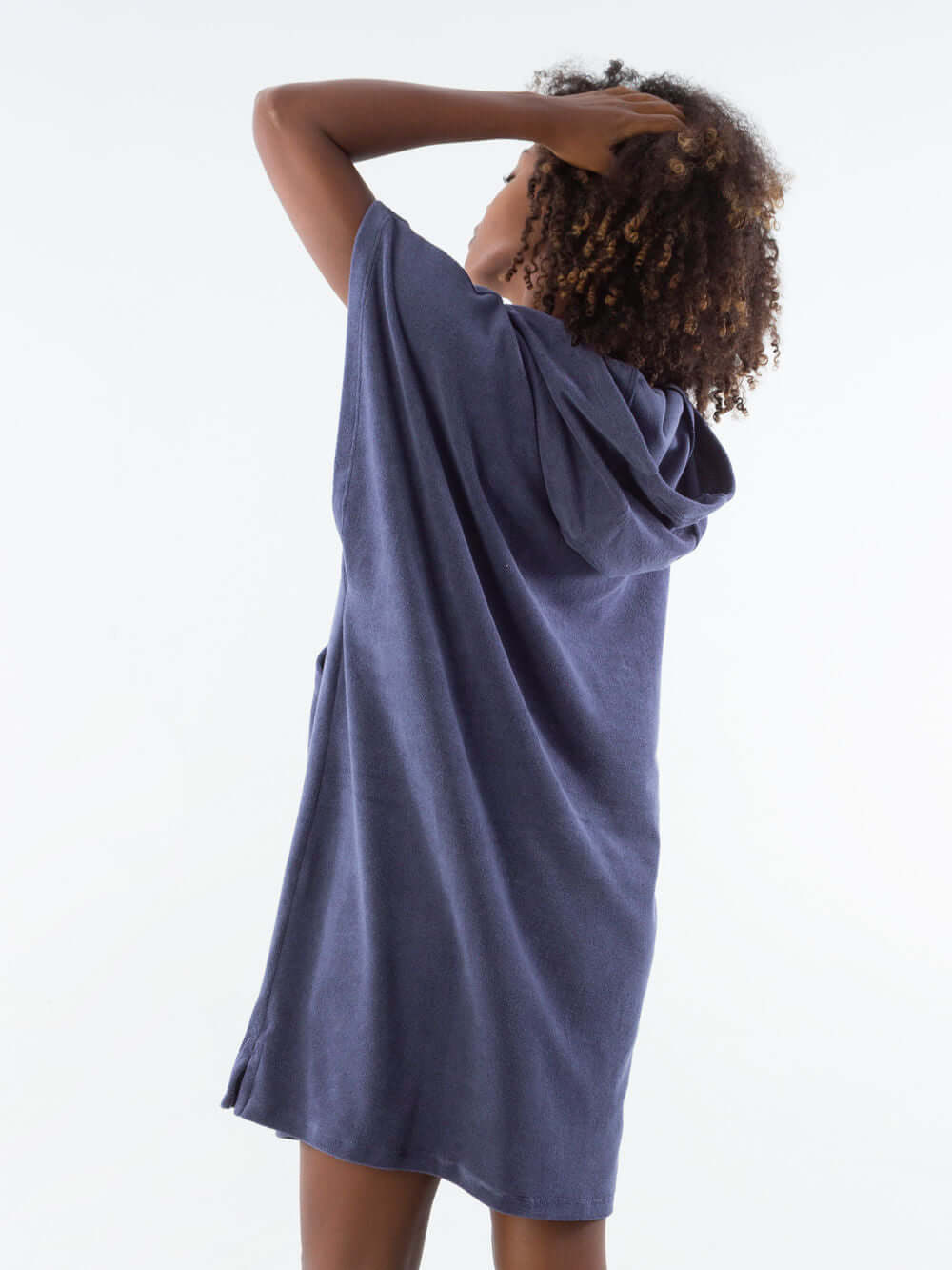 Model wearing a navy blue short towel poncho with hood, showcasing the back view.