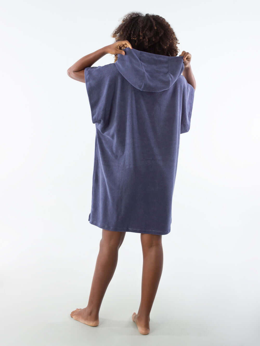 Modelo vista de costas usando poncho curto atoalhado azul marinho, ideal para praia e esportes aquáticos.