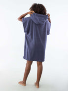 Modelo vista de costas usando poncho curto atoalhado azul marinho, ideal para praia e esportes aquáticos.