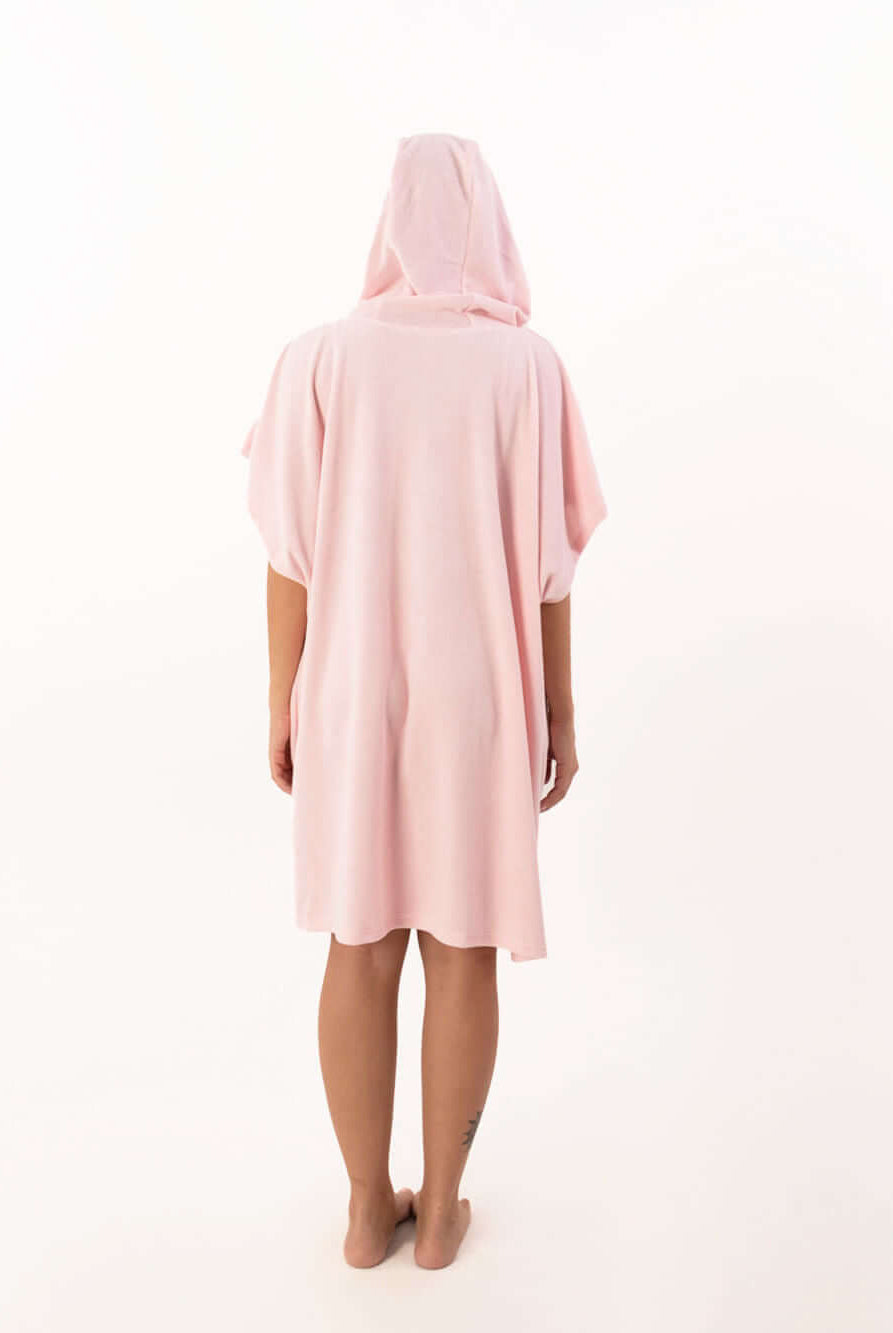 Modelo de poncho curto atoalhado rosa claro com capuz visto de costas.