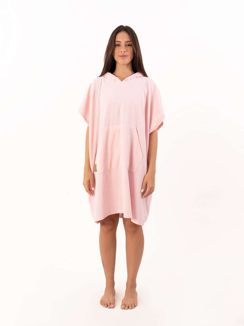 Modelo usando poncho curto atoalhado rosa claro com bolso canguru, ideal para praia e esportes aquáticos.