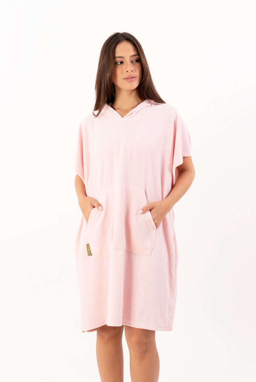 Poncho curto atoalhado rosa claro com capuz e bolsos frontais, ideal para praia e atividades aquáticas.