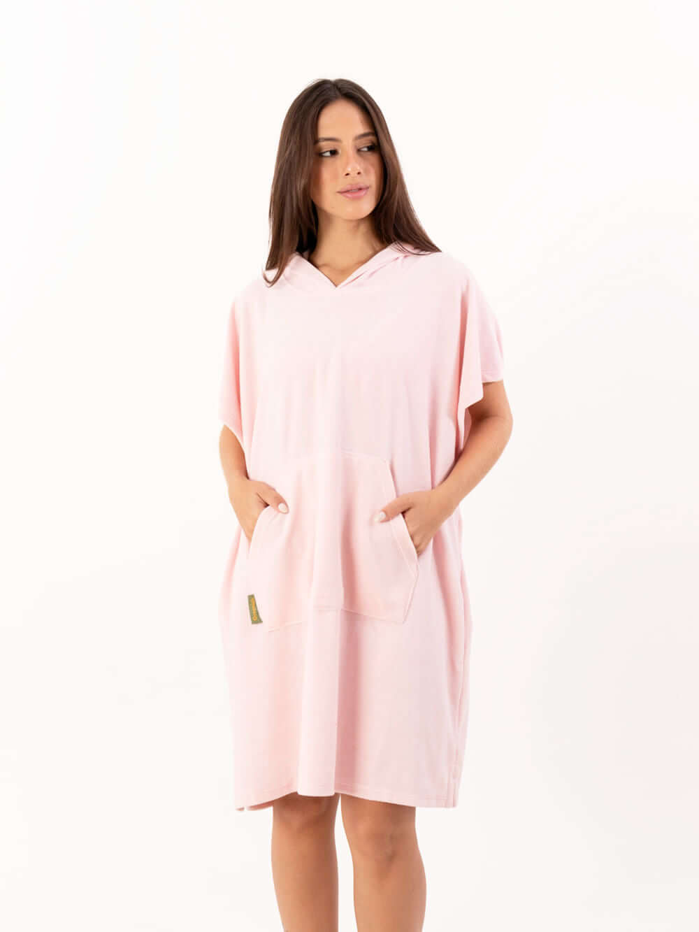 Poncho curto atoalhado rosa claro com capuz e bolsos frontais, ideal para praia e atividades aquáticas.