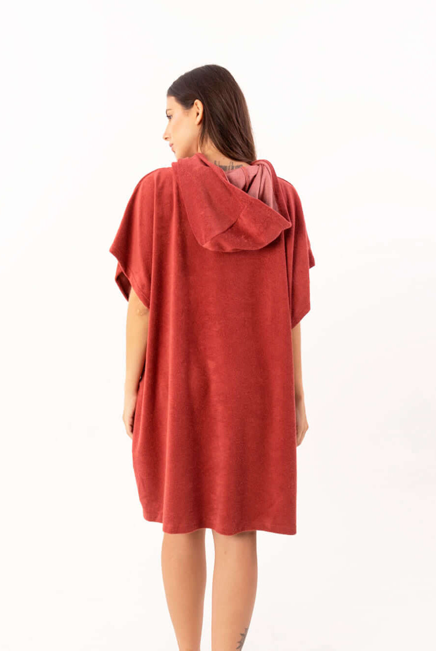 Modelo usando poncho curto atoalhado telha, com capuz e bolsos, ideal para praia e esportes aquáticos.