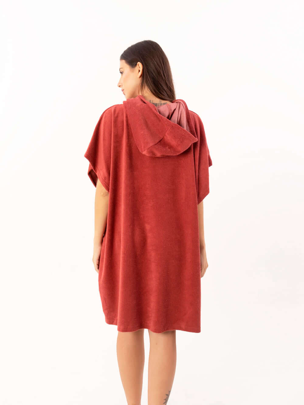 Modelo usando poncho curto atoalhado telha, com capuz e bolsos, ideal para praia e esportes aquáticos.