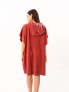 Modelo usando poncho curto atoalhado telha, com capuz e bolsos, ideal para praia e esportes aquáticos.