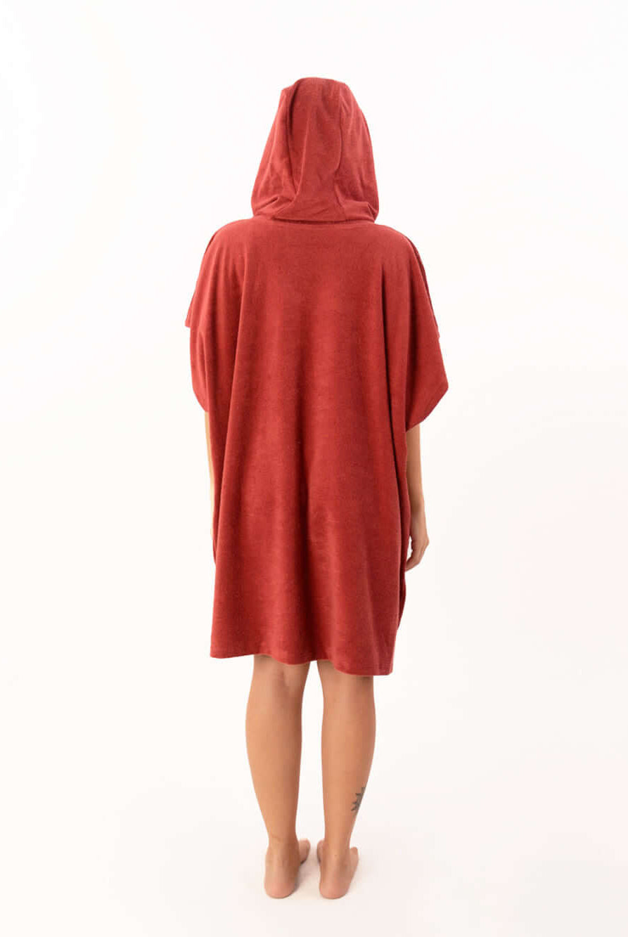 Pessoa usando poncho atoalhado telha com capuz, vista traseira, ideal para praia e esportes aquáticos.