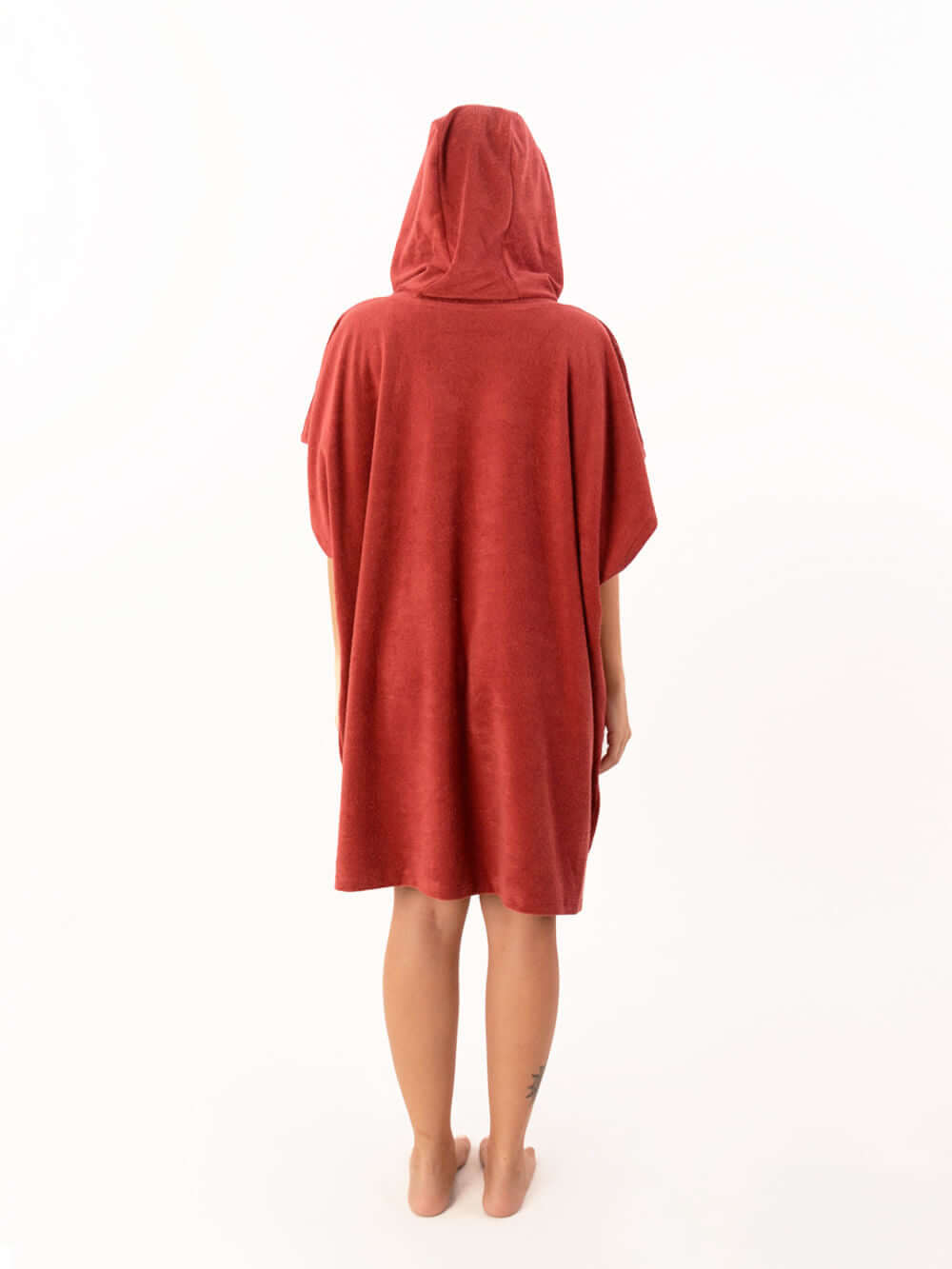 Pessoa usando poncho atoalhado telha com capuz, vista traseira, ideal para praia e esportes aquáticos.