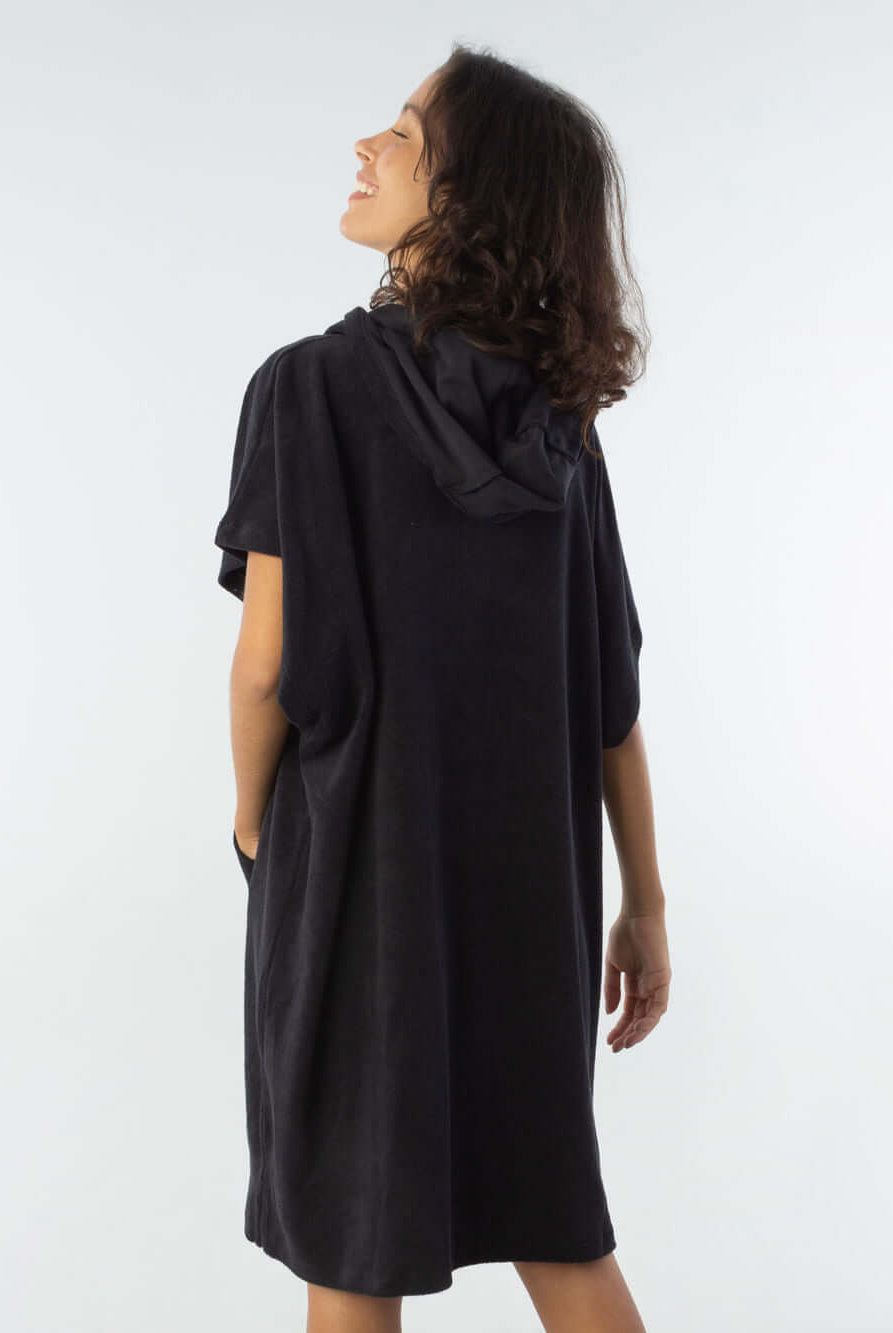 Modelo usando poncho curto atoalhado preto com bolso, perfeito para praia e esportes aquáticos.