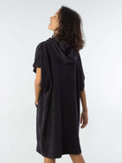 Modelo usando poncho curto atoalhado preto com bolso, perfeito para praia e esportes aquáticos.