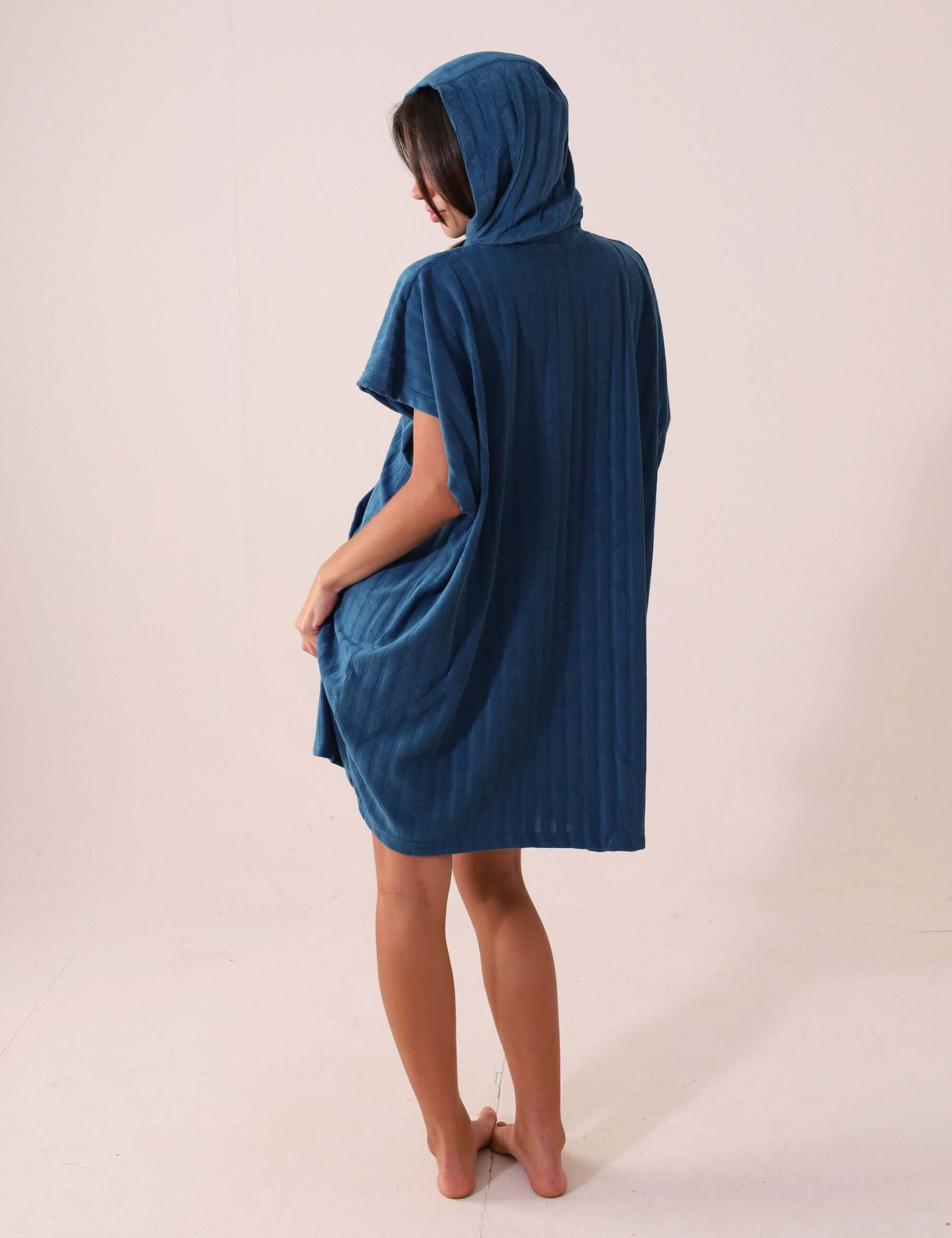 Mulher vestindo PONCHO CURTO CANELADO - AZUL Greenish com touca e bolsos canguru, feito em tecido atoalhado super absorvente e de secagem rápida.