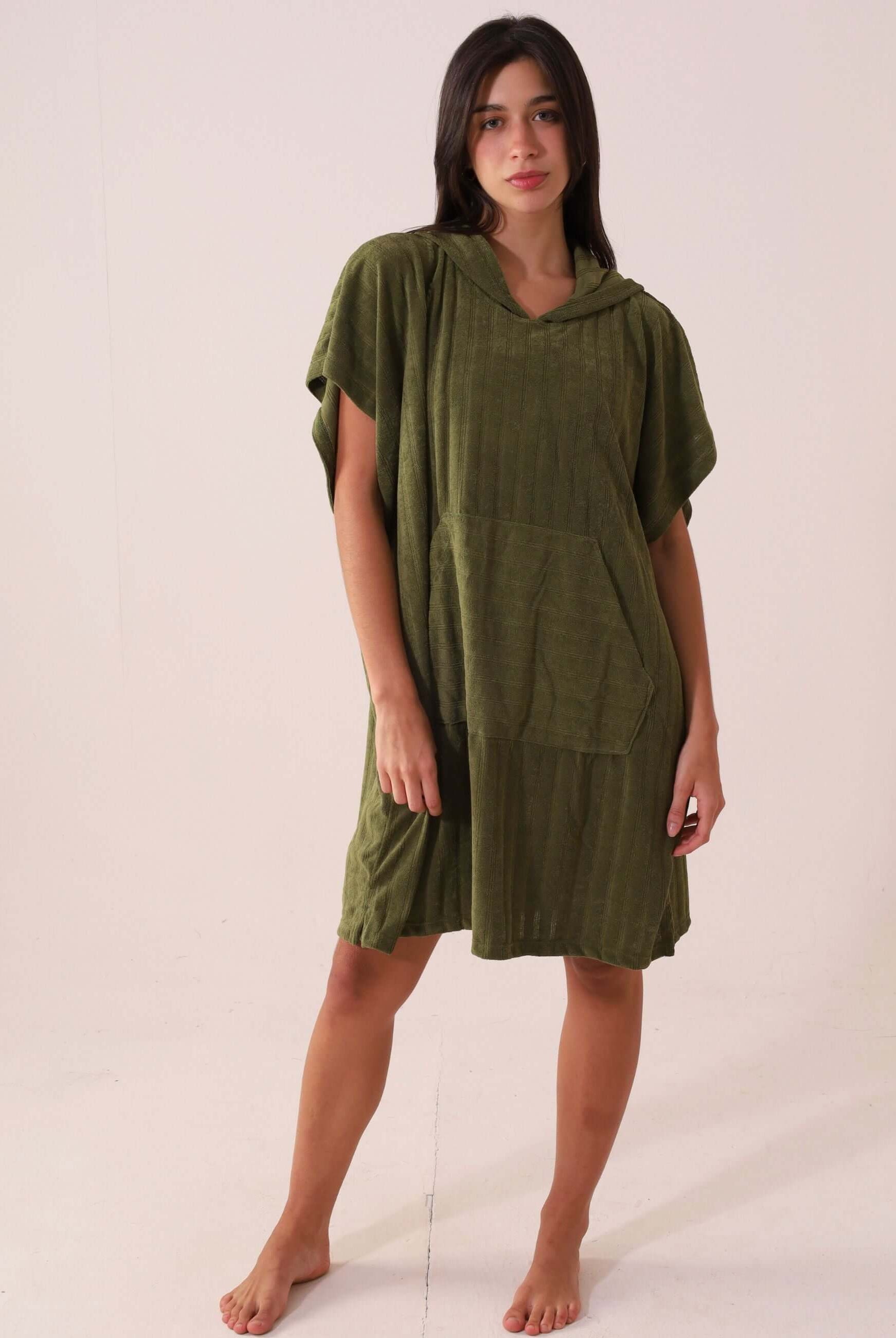 Modelo vestindo PONCHO CURTO CANELADO - VERDE Greenish, ideal para praia com tecido atoalhado e bolsos frontais.