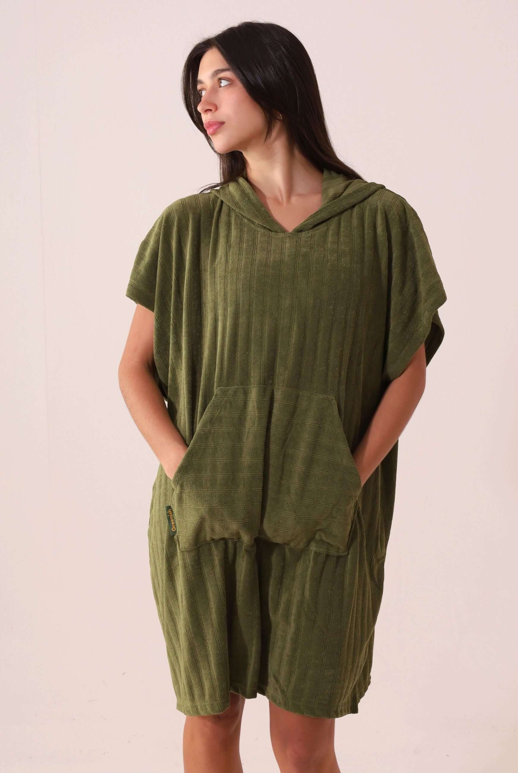 Mulher vestindo PONCHO CURTO CANELADO - VERDE da Greenish, com bolsos modelo canguru e tecido atoalhado, ideal para esportes aquáticos.