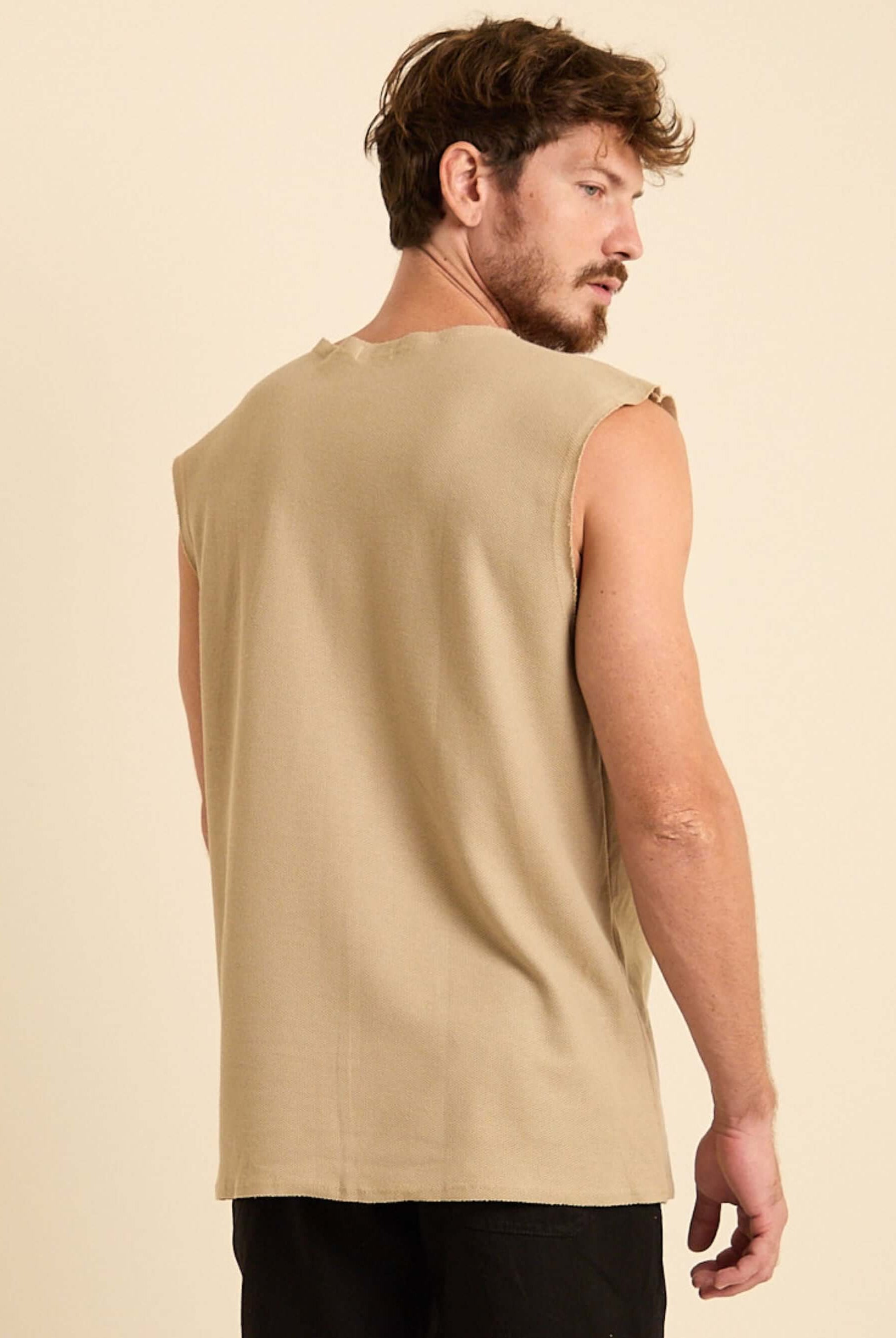Modelo masculino usando a Regata Larga Maré bege da Greenish, mostrando a parte de trás da peça.