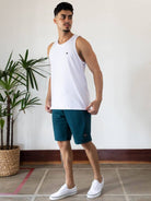 Model wearing Regata Malha Basic branca da Greenish, com calção e tênis brancos, em ambiente moderno.