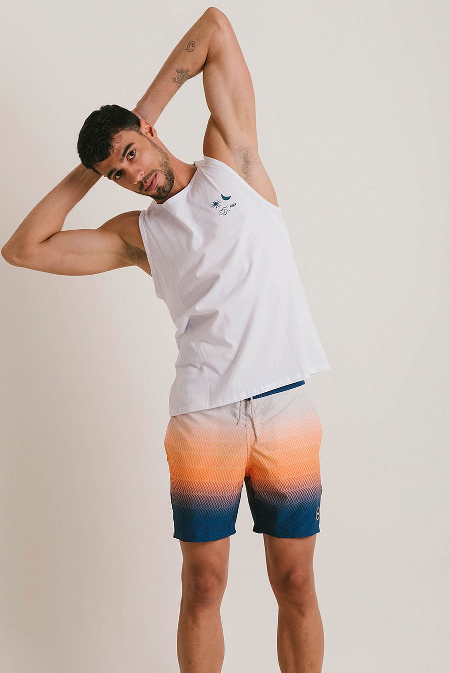 Homem fazendo alongamento com regata branca da marca Greenish e bermuda com degradê em tons de laranja e azul.