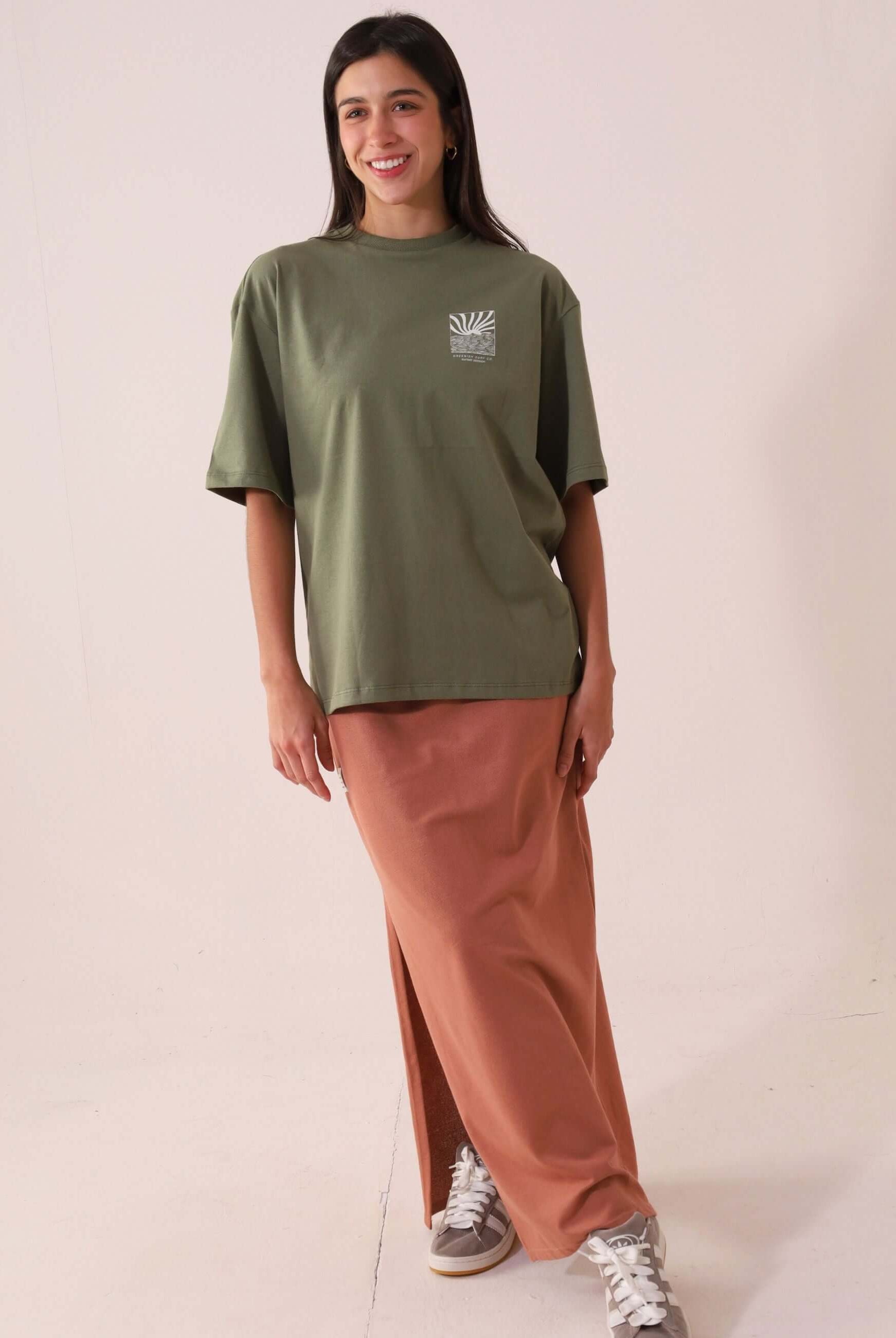 Mulher vestindo SAIA MIDI DÉA - CHOCOLATE da Greenish com camiseta verde, mostrando estilo e conforto com fenda lateral direita.