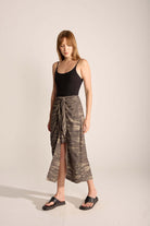 Woman in a black swimsuit wearing a chic tie dye midi skirt, showcasing a relaxed outdoor style.