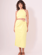 Modelo vestindo Saia Midi Sunny amarela da Greenish, feita em algodão 100%, ideal para dias ensolarados e confortáveis.