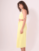 Mulher usando Saia Midi Sunny amarela da Greenish, em algodão, com cós ajustável e caimento leve, ideal para dias ao ar livre.