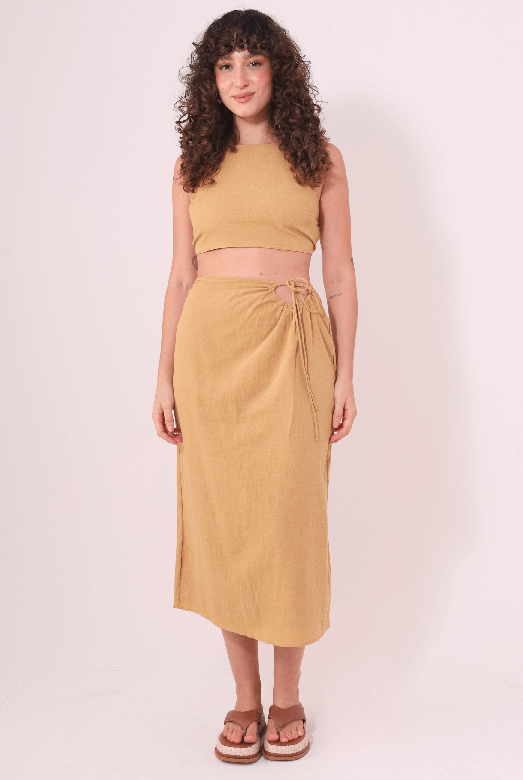 Modelo usando saia midi caqui "Sunny" da Greenish, feita em algodão e com ajuste na cintura, ideal para dias ao ar livre.