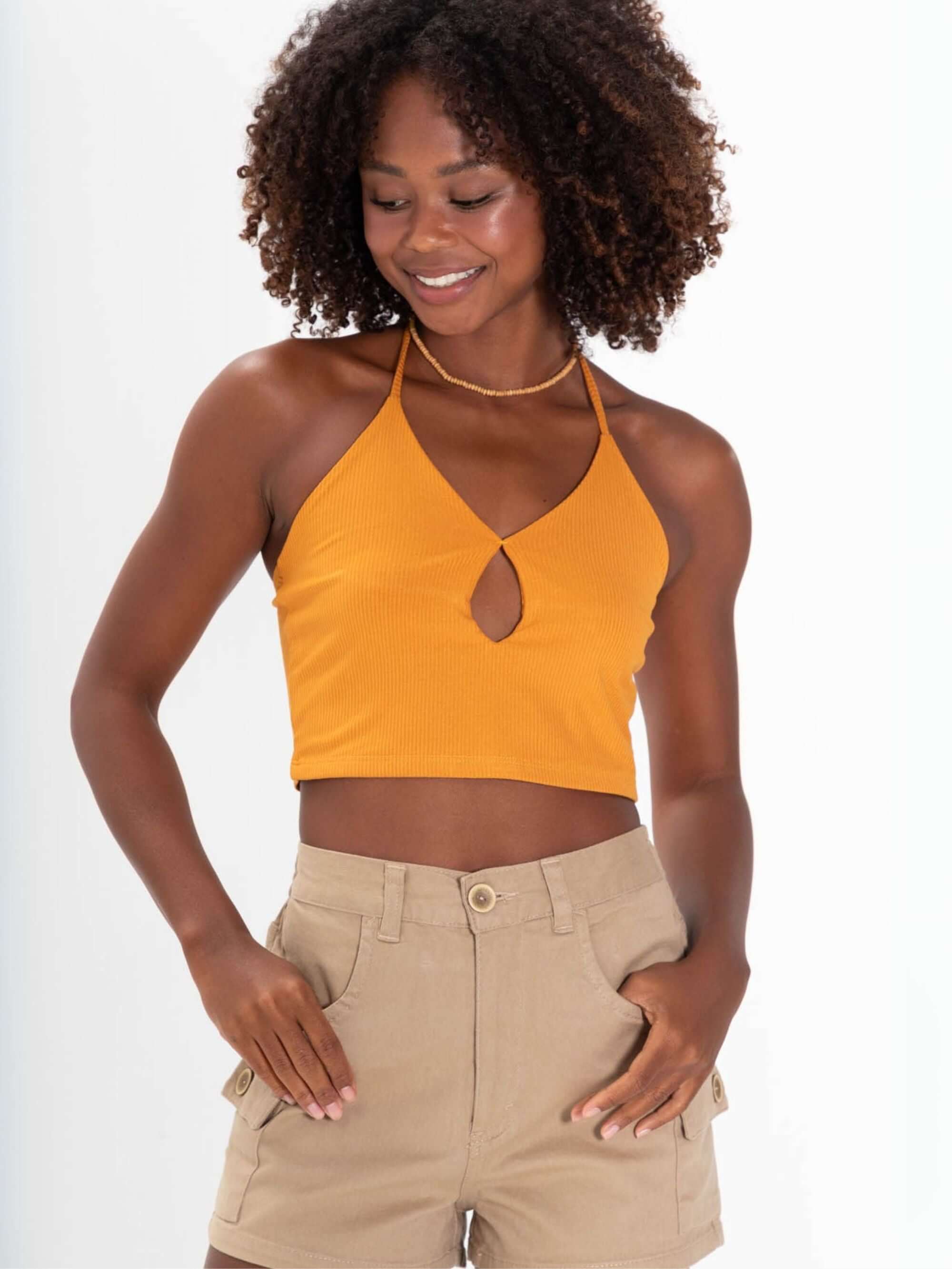 Feminino usando top laranja decotado e short cargo bege da marca Greenish, estilo casual e confortável.