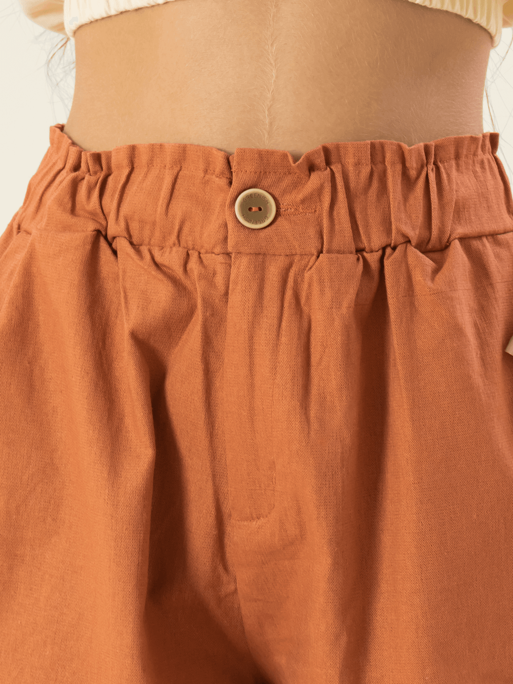 Detalhe do short feminino Peniche da marca Greenish, com cintura elástica e botão, na cor telha.
