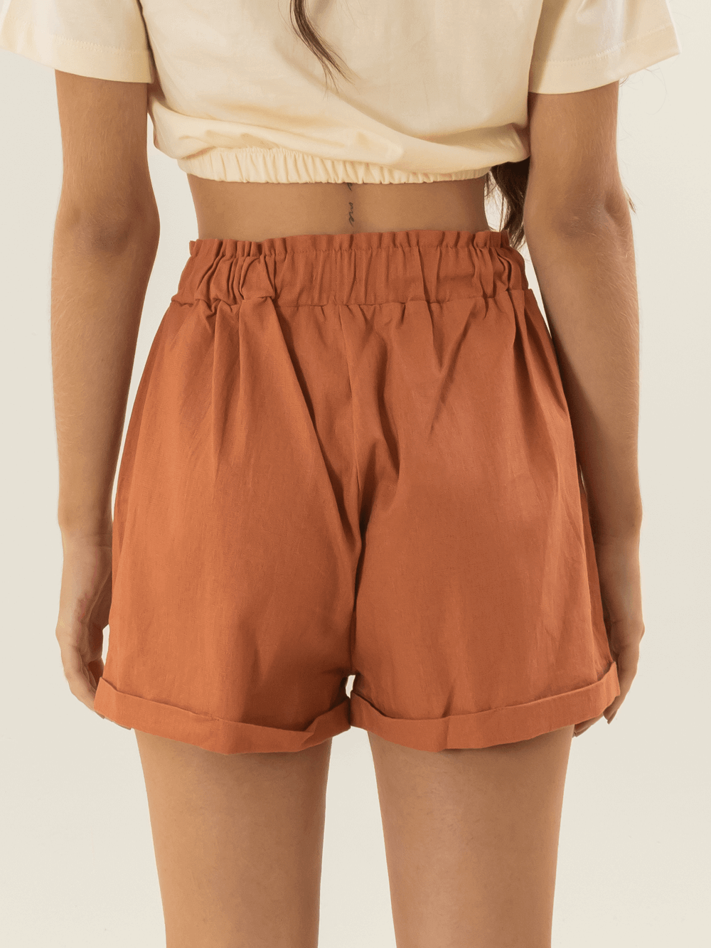 Short feminino Peniche da Greenish na cor telha, mostrando detalhes das costas e da cintura elástica.