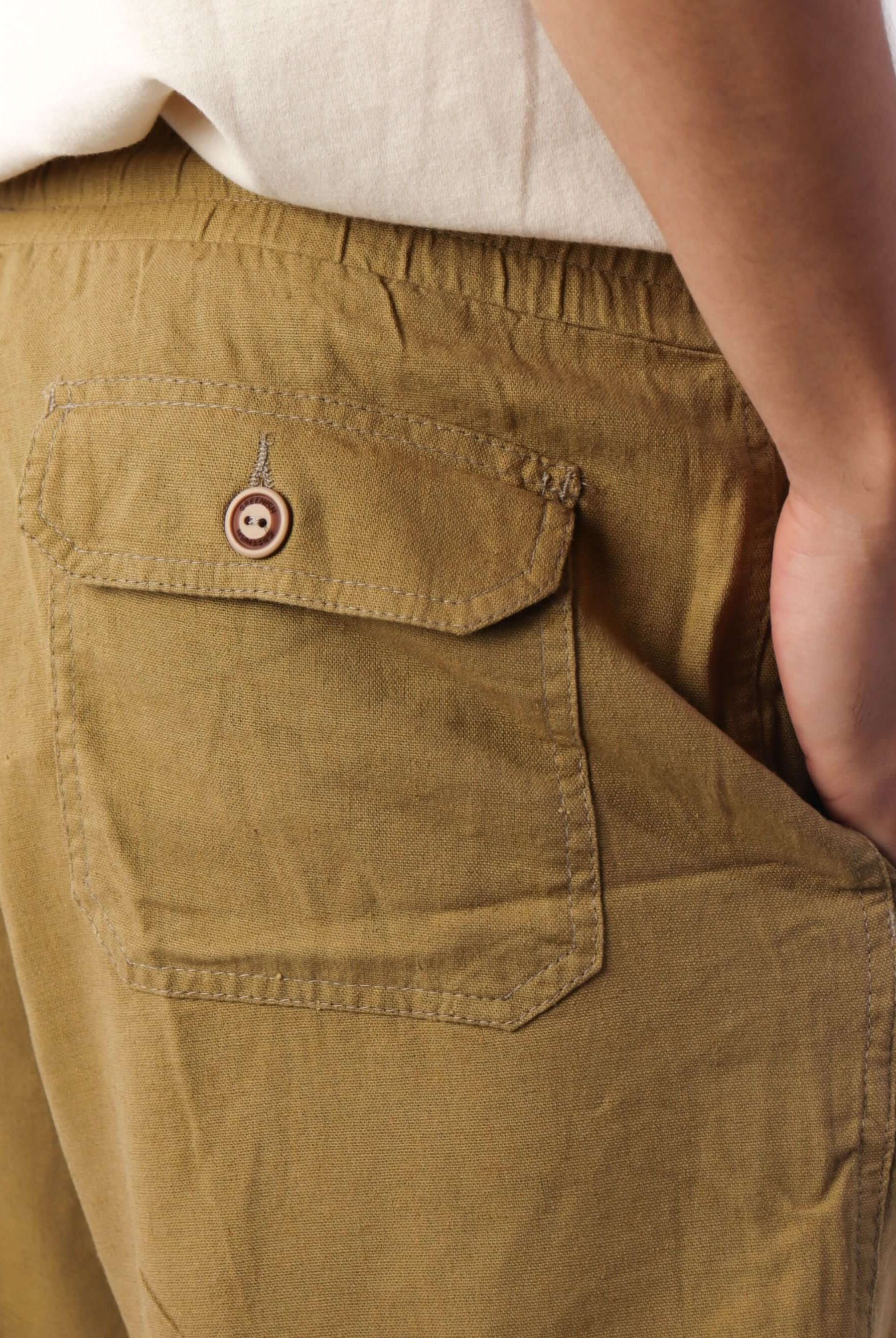 Detalhe do bolso traseiro do Short Linho Relax caqui da marca Greenish, com botão estiloso e acabamento confortável.