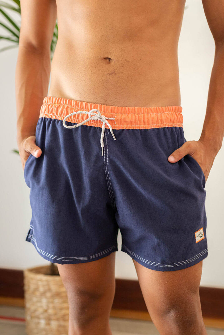 Short de vôlei azul marinho da Greenish, com detalhes em laranja, ideal para esportes e momentos à beira-mar.