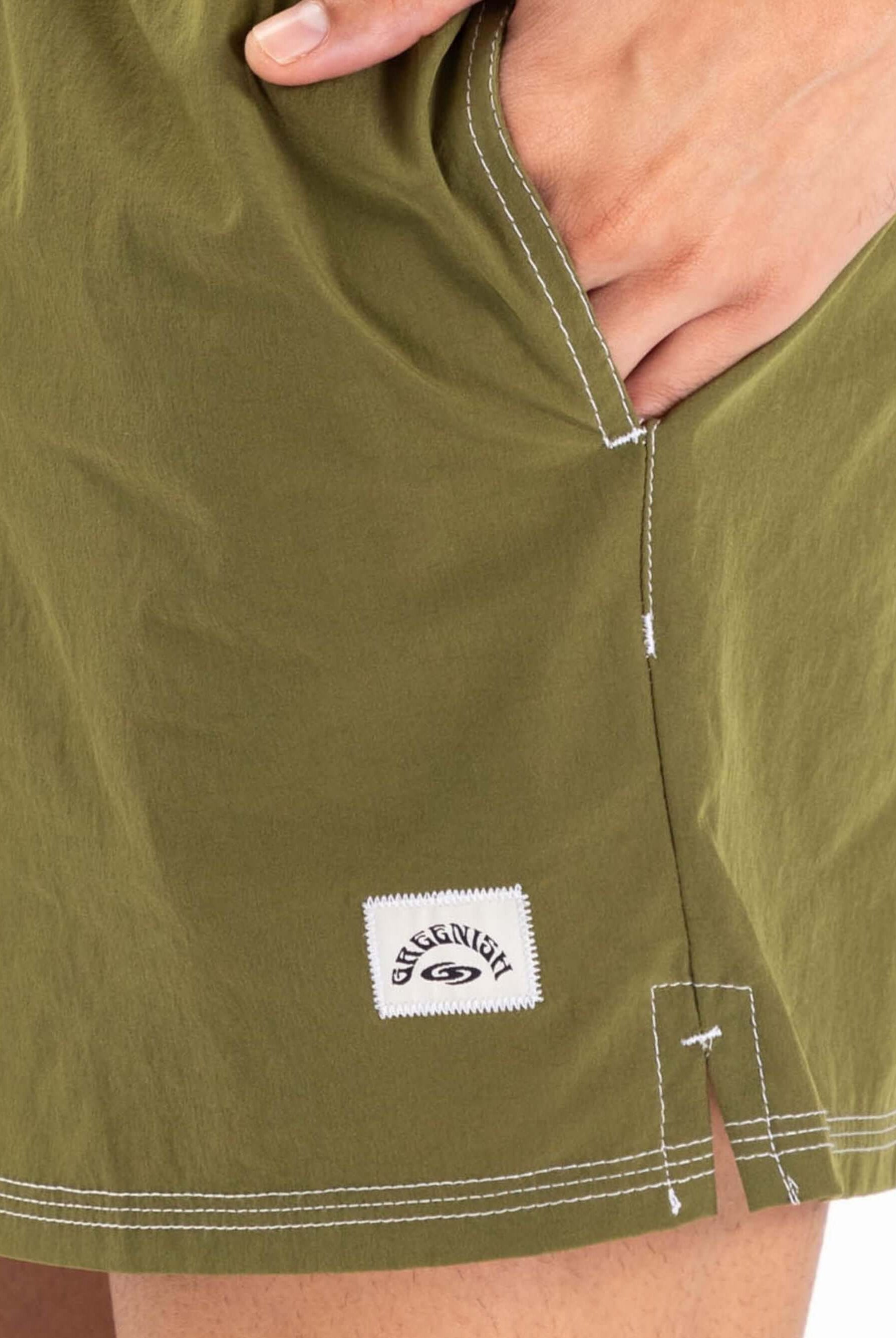 Detalhe do Short Volley Vintage Seekers Verde da Greenish, mostrando bolso lateral e etiqueta da marca.