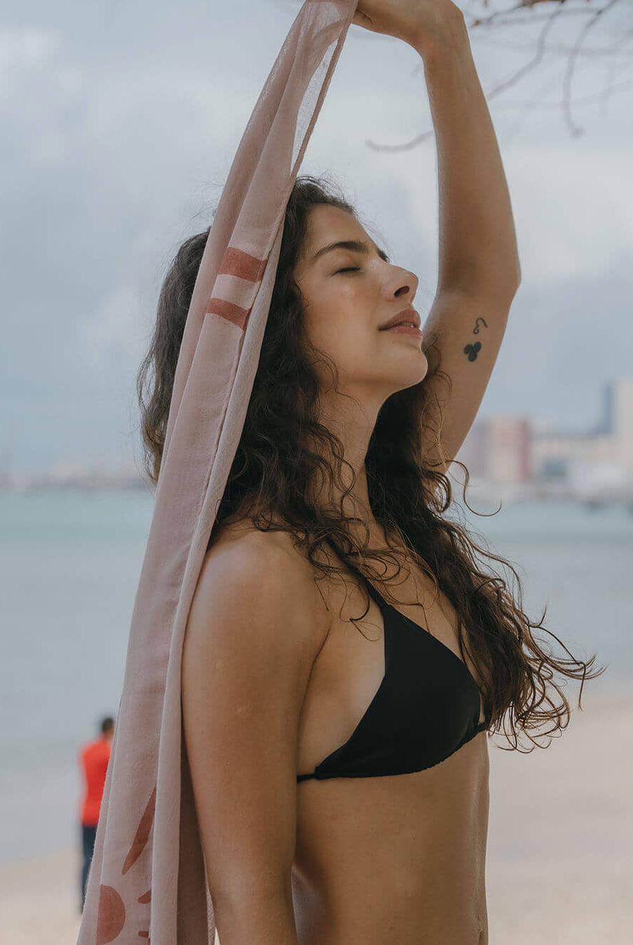 Modelo usando Sutiã Bíquini Hike da Greenish na praia com um longo lenço, aproveitando o sol.