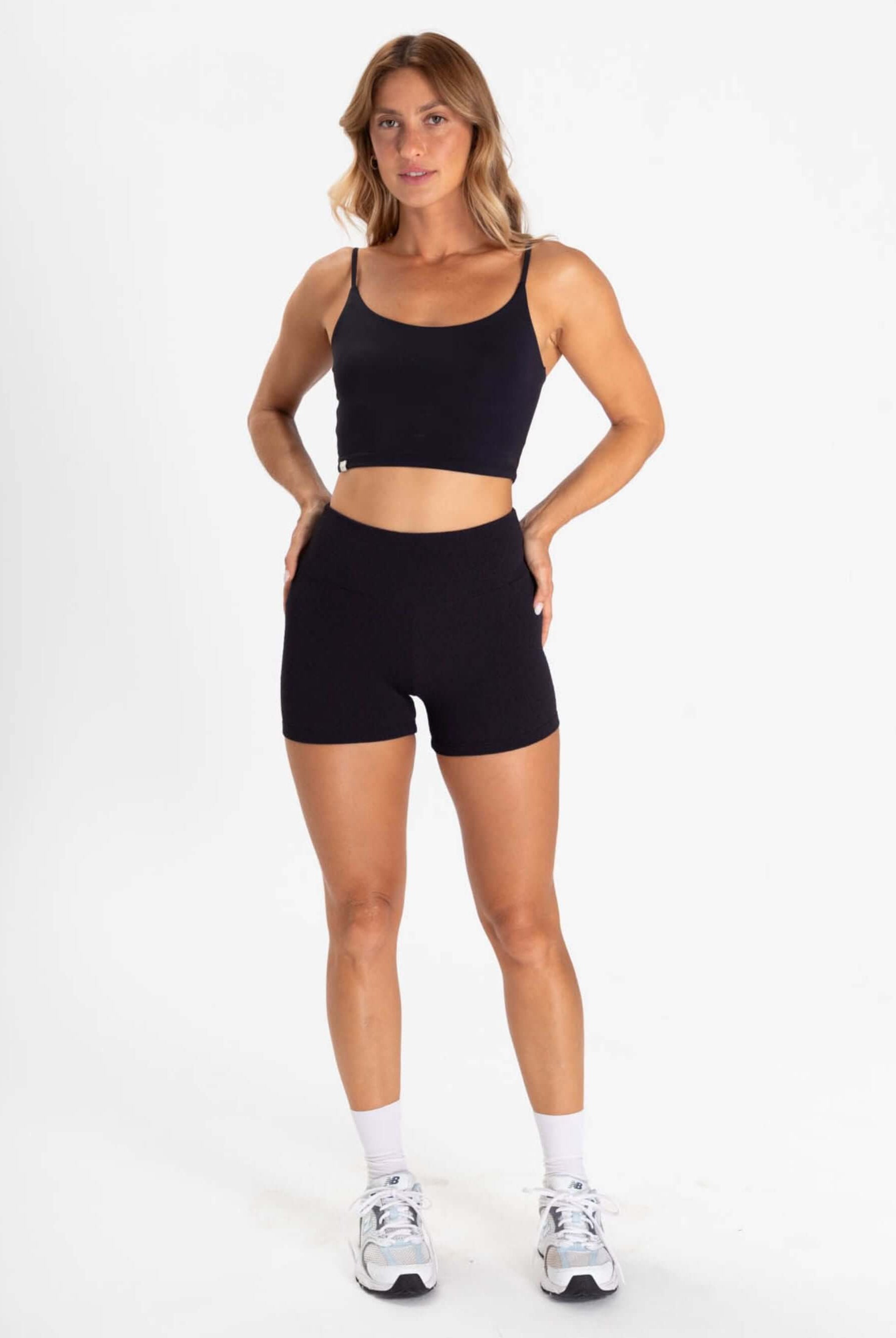 TOP ACTION - PRETO: Atleta feminina vestindo conjunto de short e cropped preto da Greenish, ideal para exercícios e conforto.