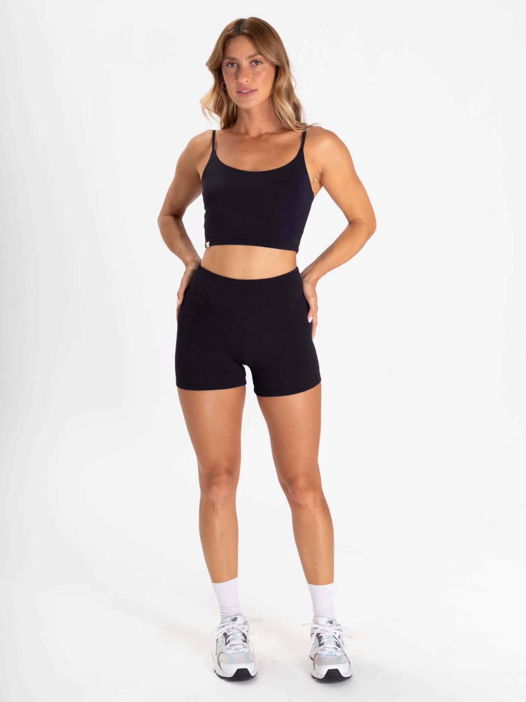 TOP ACTION - PRETO: Atleta feminina vestindo conjunto de short e cropped preto da Greenish, ideal para exercícios e conforto.