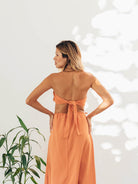 Modelo usando top bandeau Dream Days laranja da Greenish, com amarração nas costas, em ambiente iluminado.