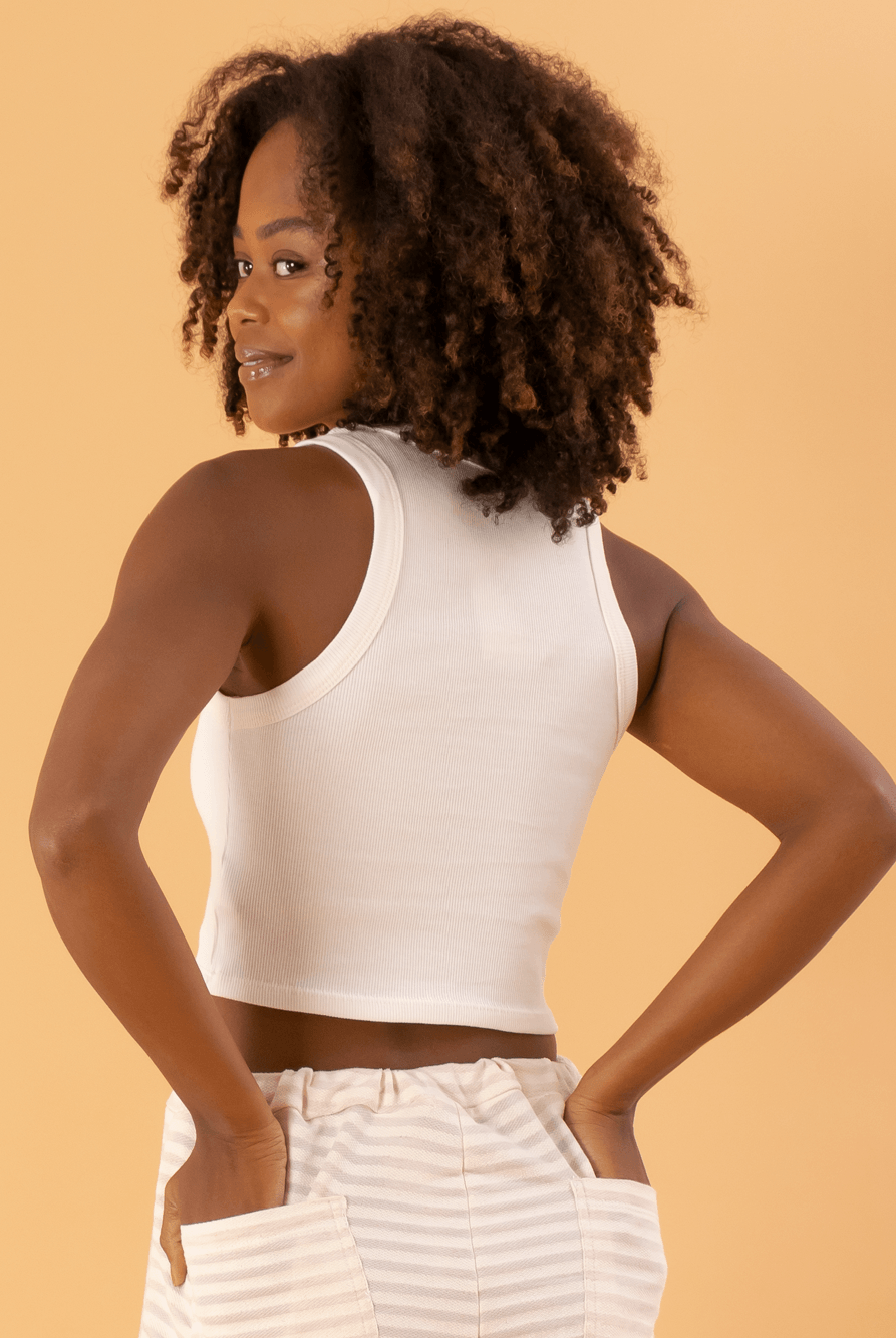 Top cropped básico em ribana off white da marca Greenish, ajustado e estiloso, exibindo costas e cabelo cacheado.
