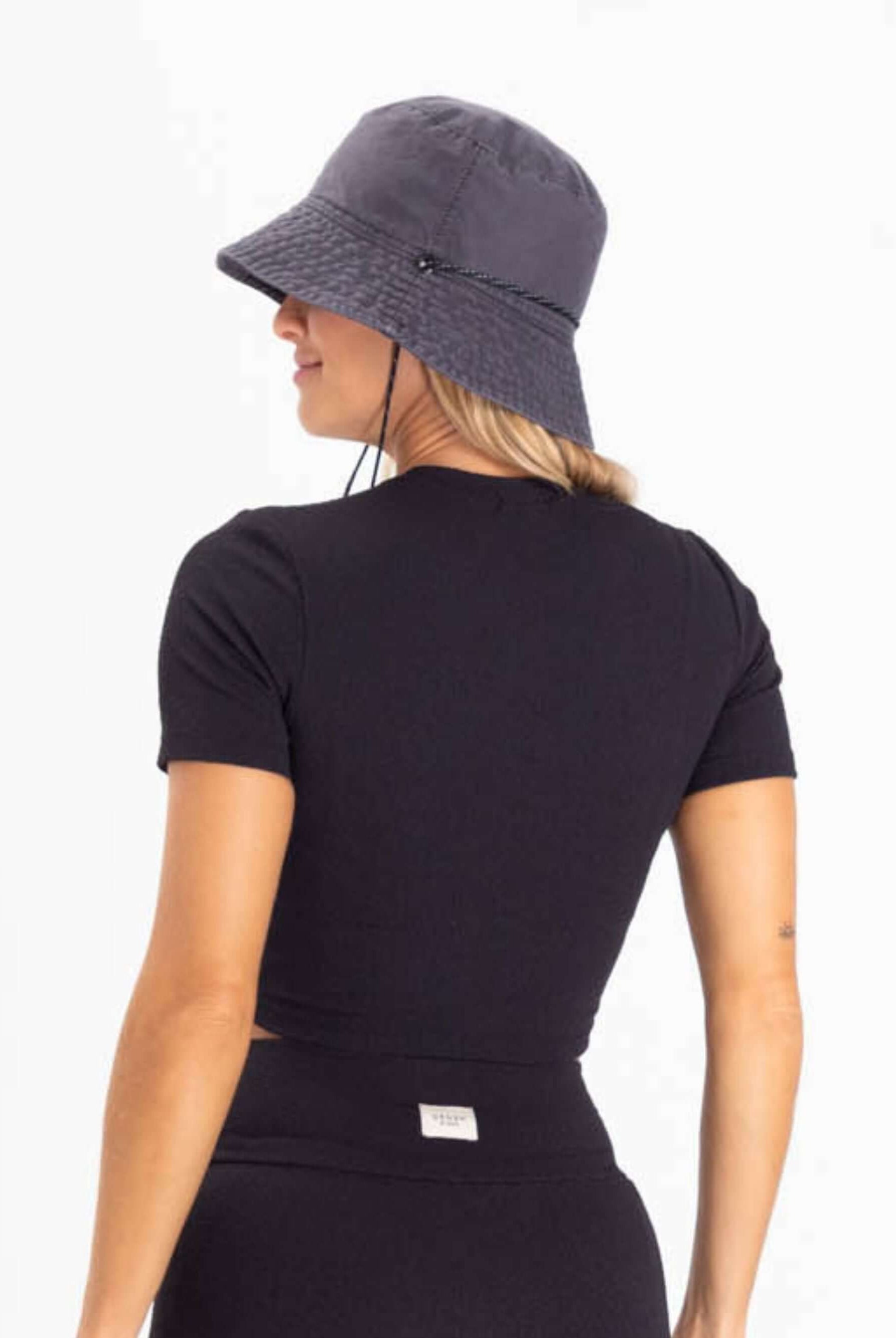 Modelo feminina usando blusa preta e chapéu, mostrando o estilo casual e moderno da Greenish.