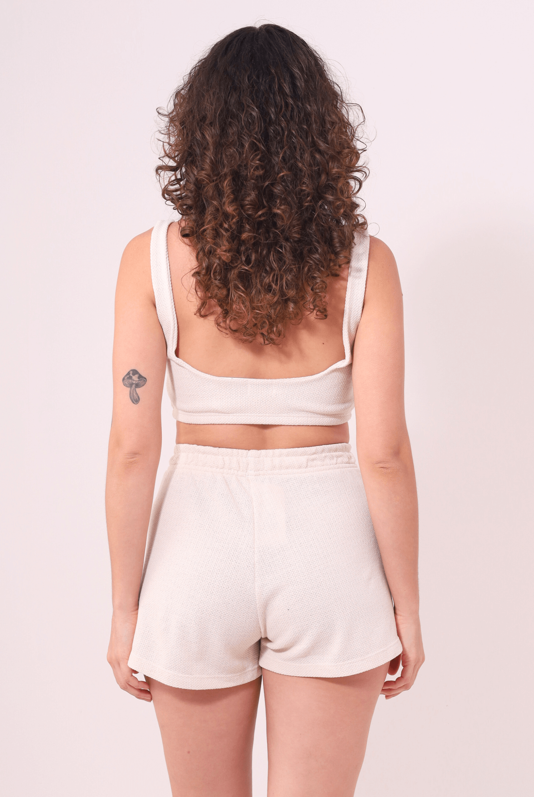 Mulher de costas vestindo Top Nalu Bege da Greenish, essencial para looks descontraídos com conforto e firmeza.