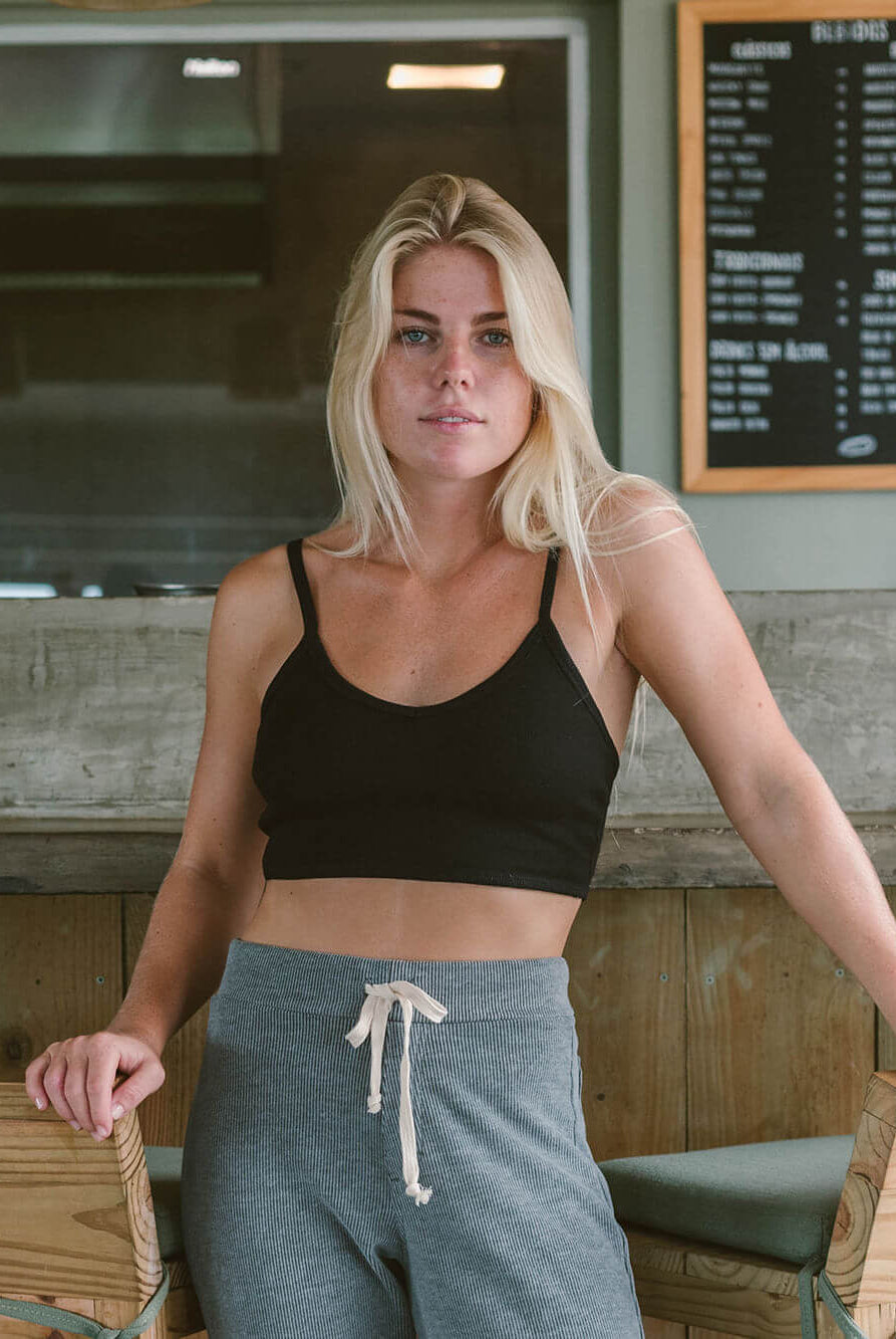 Mulher com top preto e calças cinzas, destacando conforto e estilo casual, usando produto da marca Greenish.